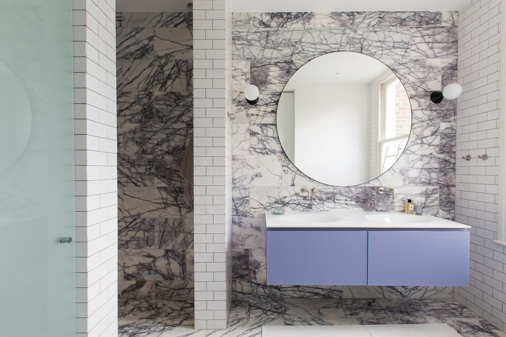 Photo of an expansive contemporary 3/4 bathroom in London with flat-panel cabinets, purple cabinets, multi-coloured walls, an integrated sink, an open shower, a wall-mount toilet, marble, marble floors, solid surface benchtops, purple floor, a hinged shower door, white benchtops, white tile, a double vanity and a floating vanity.
