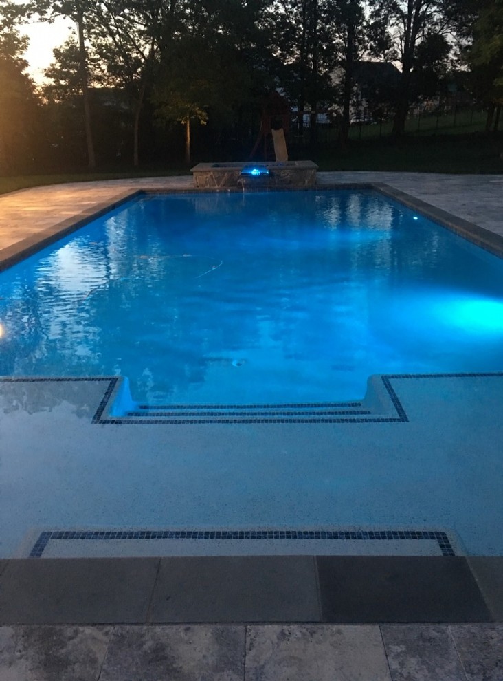 Inspiration for a large contemporary backyard rectangular lap pool in DC Metro with a water feature and natural stone pavers.