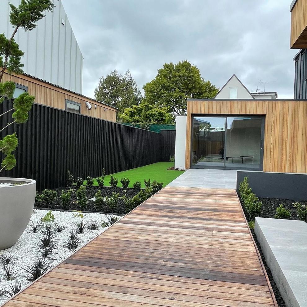 Aménagement d'un petit jardin latéral moderne avec une exposition partiellement ombragée, une terrasse en bois et une clôture en bois.