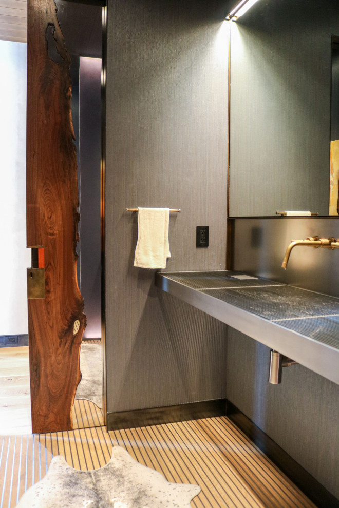 This is an example of a small contemporary shower room bathroom in Other with flat-panel cabinets, grey cabinets, a one-piece toilet, grey tiles, mirror tiles, grey walls, light hardwood flooring, an integrated sink, stainless steel worktops, beige floors, grey worktops, a single sink and a floating vanity unit.