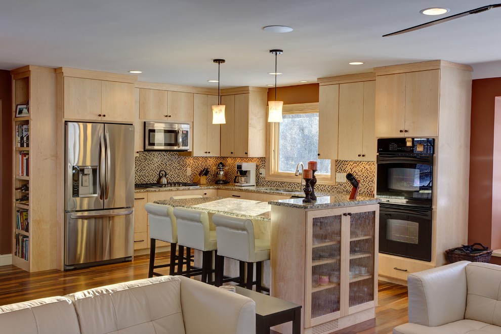 This is an example of a transitional l-shaped open plan kitchen in Minneapolis with an undermount sink, granite benchtops, mosaic tile splashback, stainless steel appliances, medium hardwood floors, flat-panel cabinets and light wood cabinets.