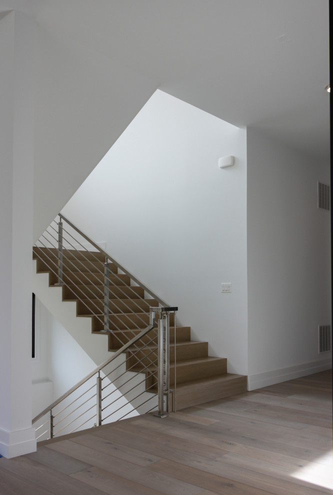 Photo of a mid-sized modern wood floating staircase in DC Metro with wood risers, metal railing and planked wall panelling.