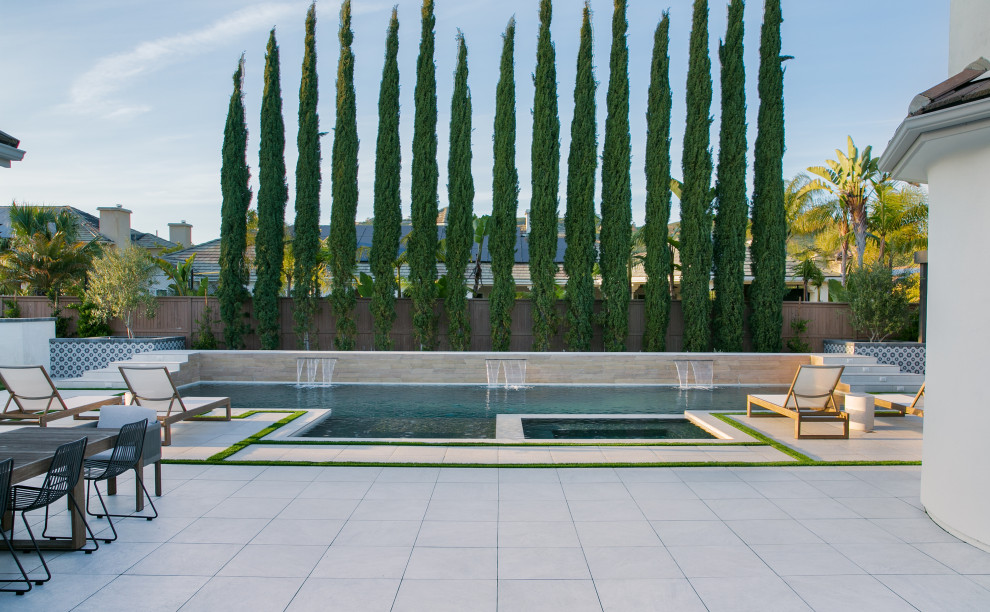 Свежая идея для дизайна: большой прямоугольный ландшафтный бассейн на заднем дворе в стиле неоклассика (современная классика) с покрытием из плитки - отличное фото интерьера