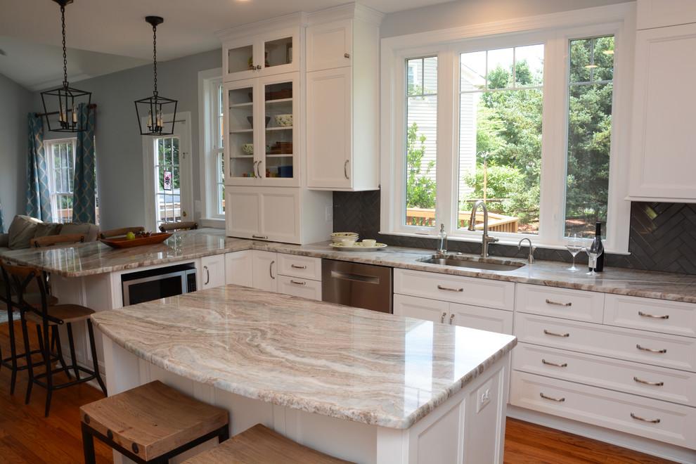 This is an example of a large transitional l-shaped separate kitchen in DC Metro with an undermount sink, recessed-panel cabinets, white cabinets, granite benchtops, black splashback, stainless steel appliances, light hardwood floors, with island, brown floor and beige benchtop.