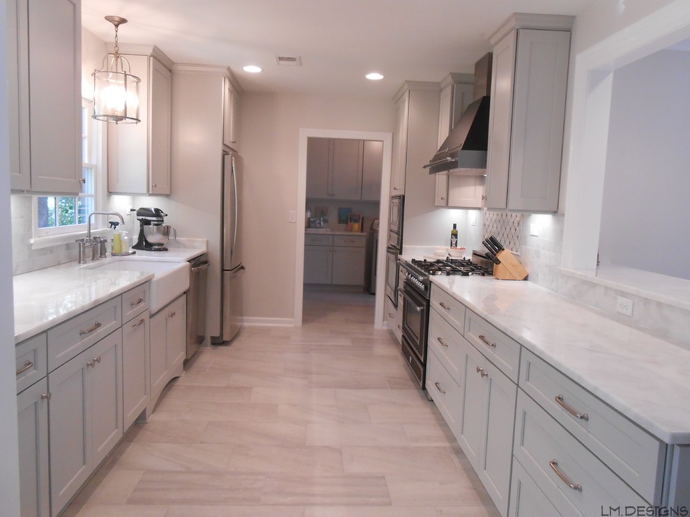 Example of a transitional galley porcelain tile eat-in kitchen design with a farmhouse sink, recessed-panel cabinets, gray cabinets, marble countertops, stone tile backsplash, stainless steel appliances and a peninsula
