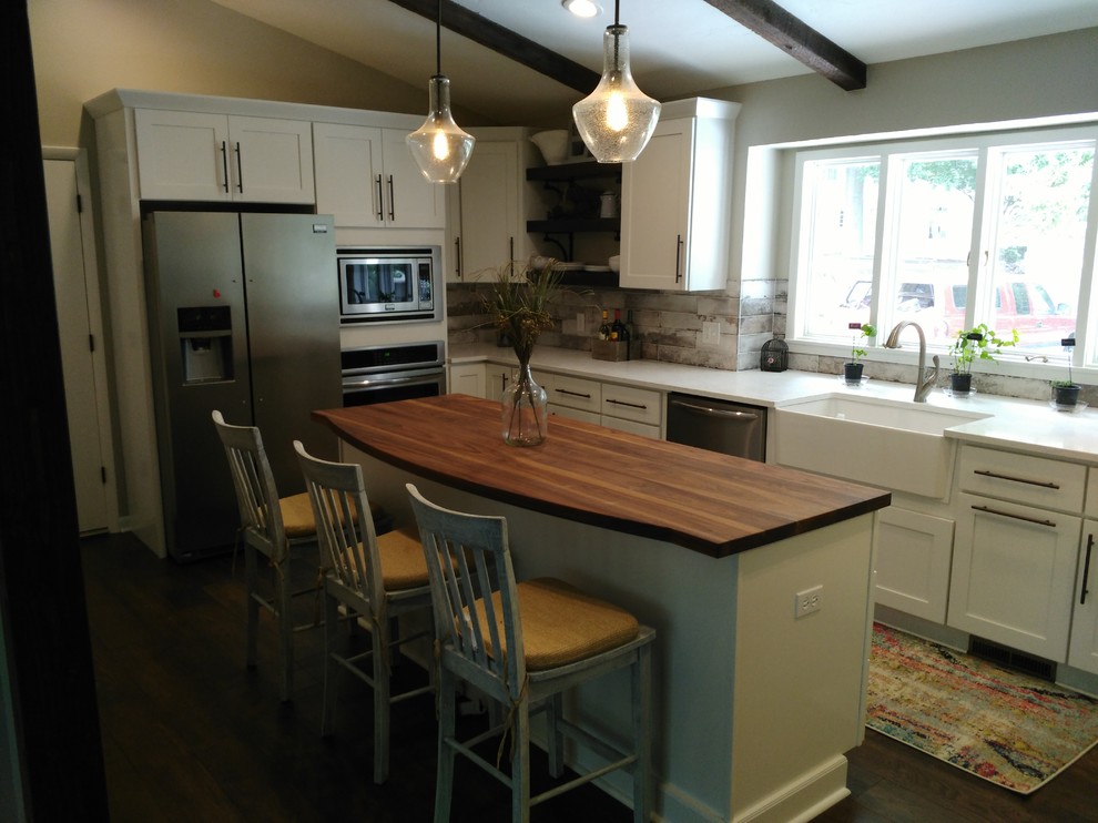 Eat-in kitchen - mid-sized transitional l-shaped dark wood floor and brown floor eat-in kitchen idea with a farmhouse sink, shaker cabinets, white cabinets, wood countertops, gray backsplash, marble backsplash, stainless steel appliances and an island