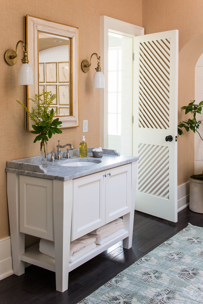 Inspiration for a mid-sized traditional 3/4 bathroom in Birmingham with white cabinets, recessed-panel cabinets, a shower/bathtub combo, white tile, subway tile, dark hardwood floors, an undermount sink, marble benchtops, an alcove tub, beige walls, brown floor and a shower curtain.