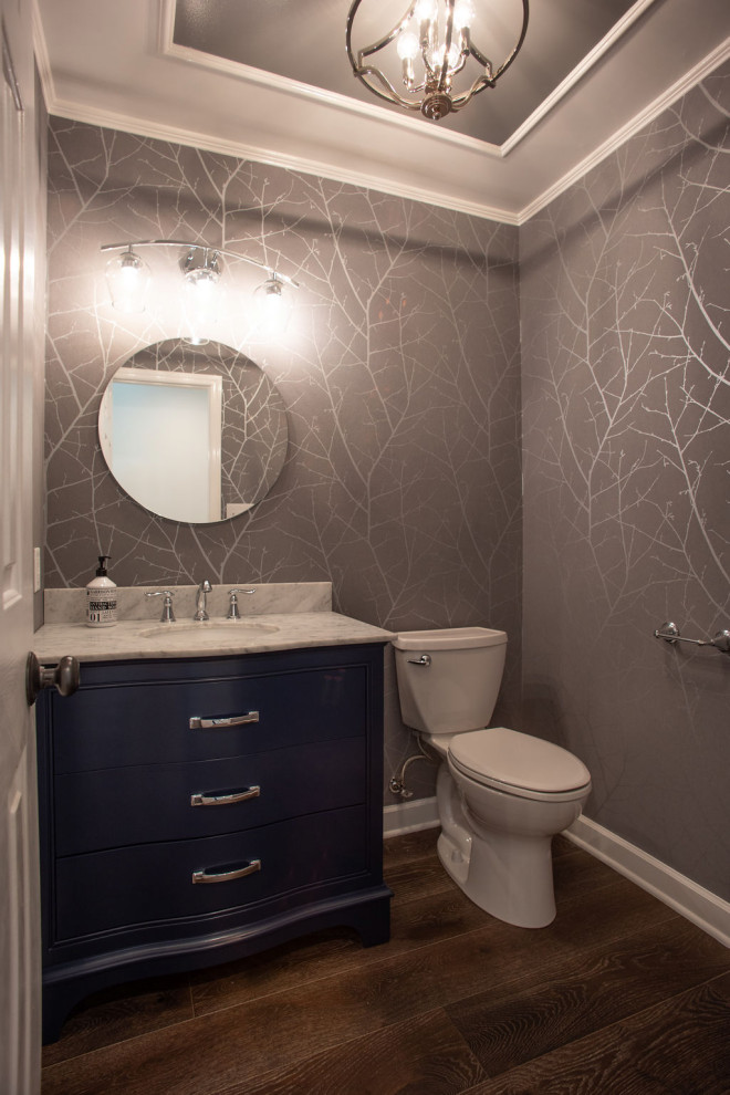 Design ideas for a small transitional powder room in Other with blue cabinets, a two-piece toilet, grey walls, medium hardwood floors, an undermount sink, marble benchtops, multi-coloured floor, white benchtops, a freestanding vanity, recessed and wallpaper.