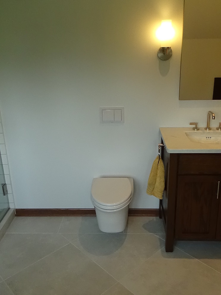Freestanding bathtub - mid-sized transitional master white tile and ceramic tile porcelain tile and beige floor freestanding bathtub idea in Chicago with recessed-panel cabinets, medium tone wood cabinets, a wall-mount toilet, white walls, an undermount sink, quartz countertops, a hinged shower door and white countertops