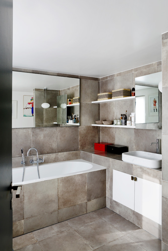 Photo of a mid-sized contemporary master bathroom in Paris with a vessel sink, flat-panel cabinets, white cabinets, gray tile, a drop-in tub and grey walls.