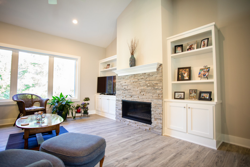 Rustikales Wohnzimmer mit Vinylboden, Kamin, Kaminumrandung aus gestapelten Steinen, Eck-TV und grauem Boden in Grand Rapids