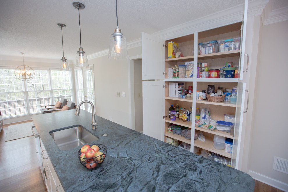 Large eclectic galley open plan kitchen in Atlanta with a drop-in sink, shaker cabinets, white cabinets, soapstone benchtops, grey splashback, glass tile splashback, stainless steel appliances, light hardwood floors and with island.