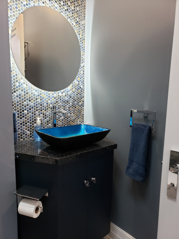 This is an example of a modern bathroom in Toronto with flat-panel cabinets, black cabinets, an alcove shower, a one-piece toilet, blue tile, mosaic tile, blue walls, porcelain floors, a vessel sink, granite benchtops, blue floor, a hinged shower door, black benchtops, a single vanity and a built-in vanity.