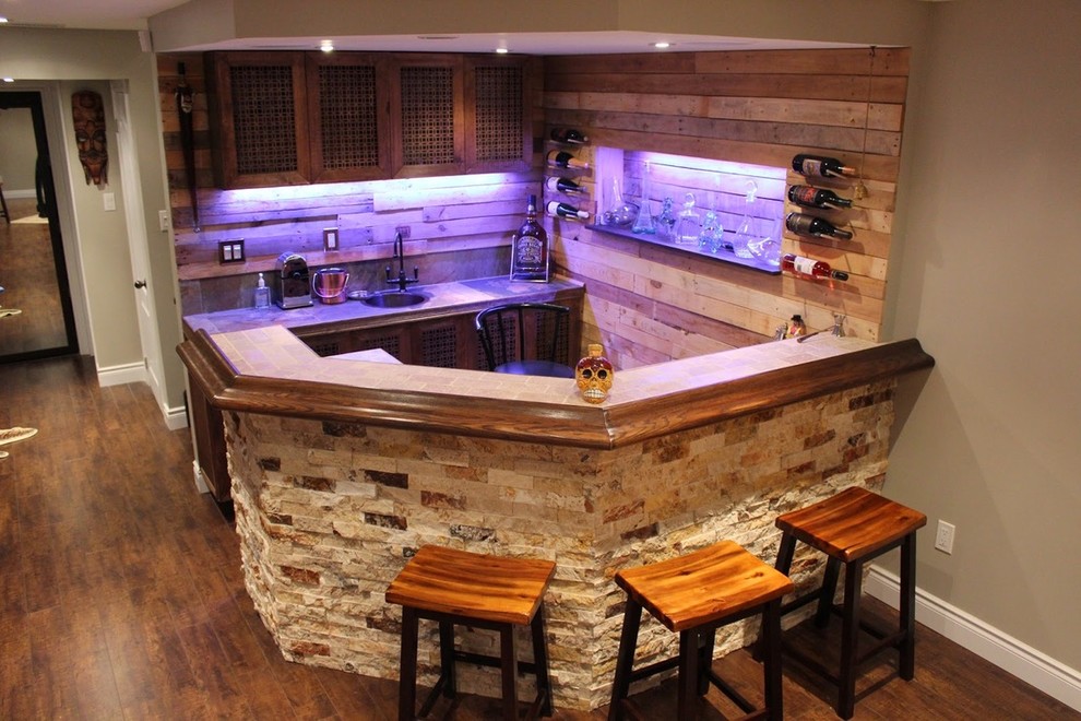 This is an example of a large eclectic u-shaped wet bar in Toronto with a drop-in sink, brown cabinets, tile benchtops, brown splashback, ceramic splashback and porcelain floors.