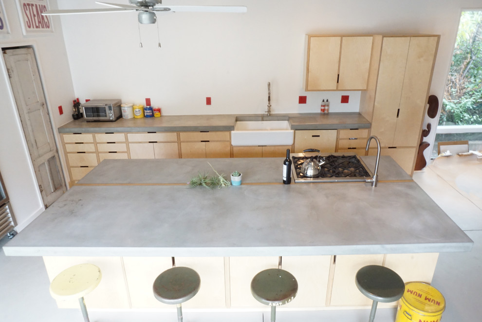 This is an example of a large modern single-wall eat-in kitchen in Denver with a farmhouse sink, flat-panel cabinets, light wood cabinets, concrete benchtops, concrete floors, with island, grey floor and grey benchtop.