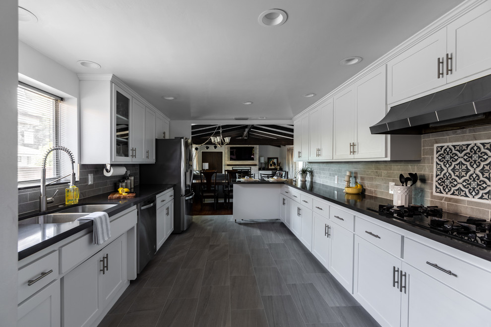 Large transitional galley porcelain tile and gray floor enclosed kitchen photo in Orange County with an undermount sink, shaker cabinets, white cabinets, gray backsplash, porcelain backsplash, stainless steel appliances, no island and black countertops