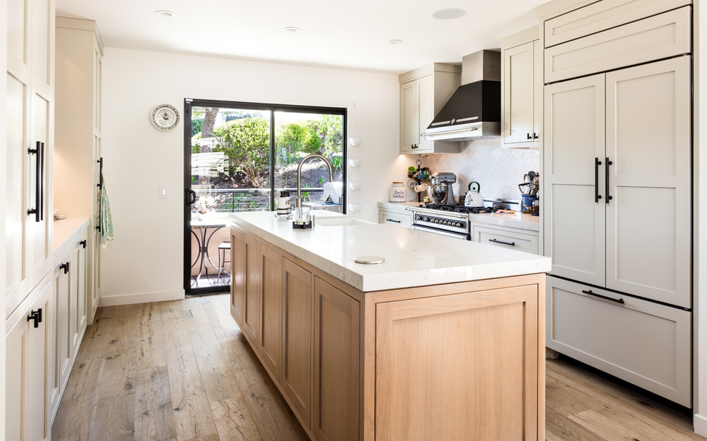 Design ideas for a small transitional galley eat-in kitchen in Los Angeles with a farmhouse sink, shaker cabinets, beige cabinets, quartz benchtops, beige splashback, ceramic splashback, stainless steel appliances, light hardwood floors, with island, beige floor and beige benchtop.