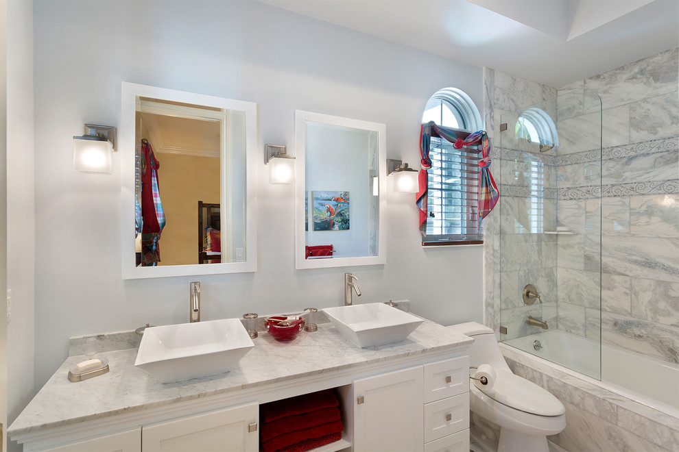 Mid-sized mediterranean master bathroom in Miami with recessed-panel cabinets, white cabinets, an alcove tub, a shower/bathtub combo, a one-piece toilet, gray tile, marble, blue walls, a vessel sink, marble benchtops, an open shower and grey benchtops.