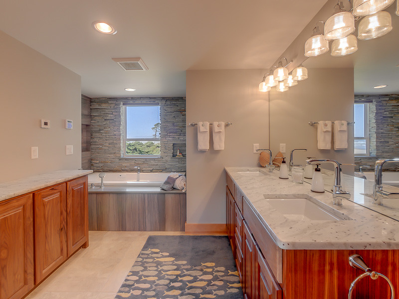 Photo of a large beach style master bathroom in Portland with raised-panel cabinets, medium wood cabinets, a drop-in tub, grey walls, ceramic floors, an undermount sink, beige floor, grey benchtops, a double vanity and a built-in vanity.