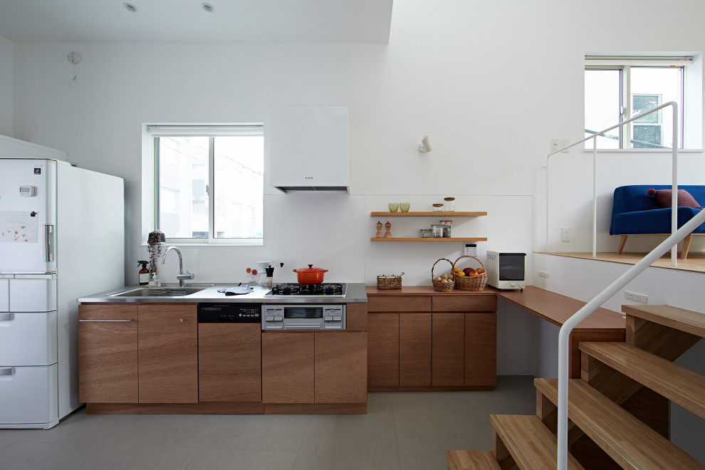 Photo of a contemporary single-wall kitchen in Tokyo with an integrated sink, flat-panel cabinets, medium wood cabinets, stainless steel benchtops, white splashback, white appliances, grey floor and grey benchtop.