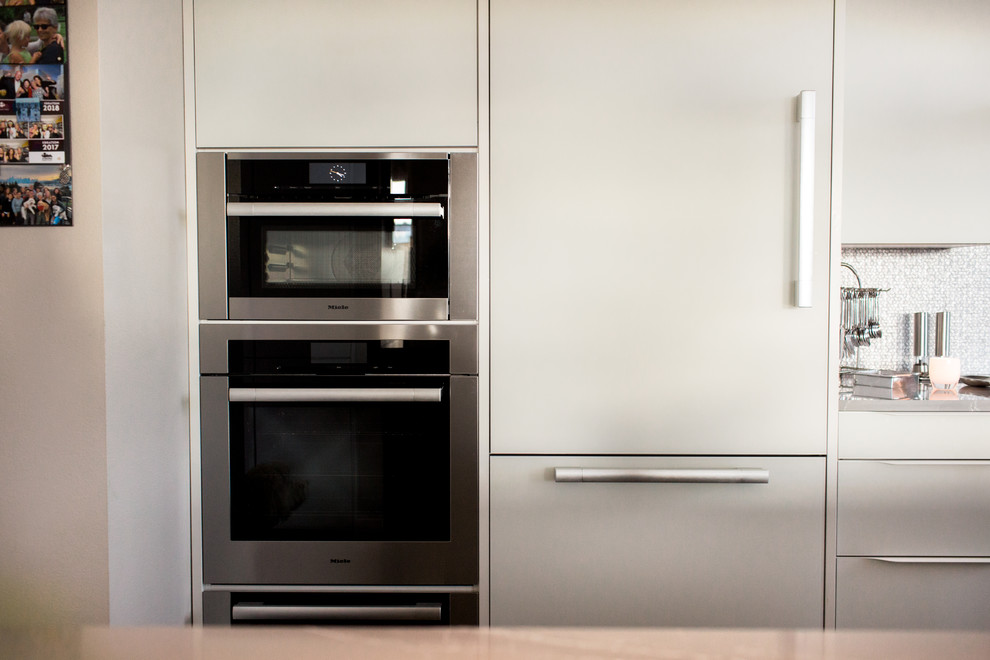 Eat-in kitchen - mid-sized modern galley dark wood floor and brown floor eat-in kitchen idea in Seattle with a single-bowl sink, flat-panel cabinets, white cabinets, quartzite countertops, white backsplash, mosaic tile backsplash, stainless steel appliances, no island and white countertops