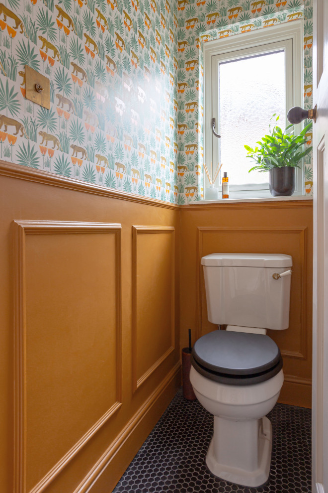 Exempel på ett litet klassiskt toalett, med orange väggar och svart golv