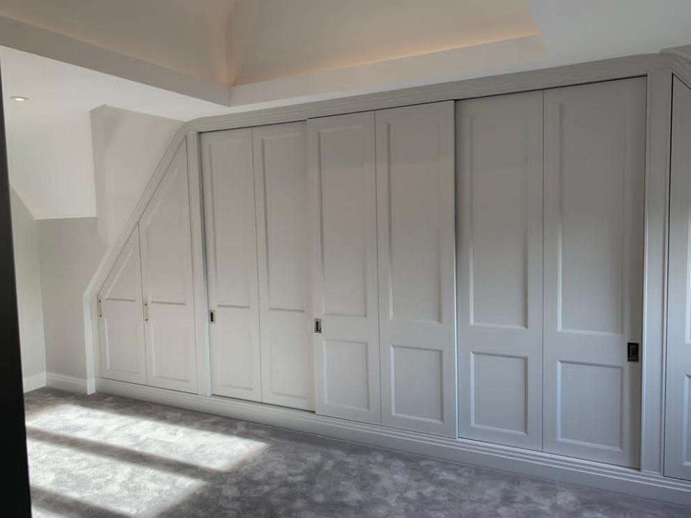 Idée de décoration pour une grande armoire encastrée design neutre avec un placard à porte shaker, des portes de placard grises, moquette et un plafond à caissons.