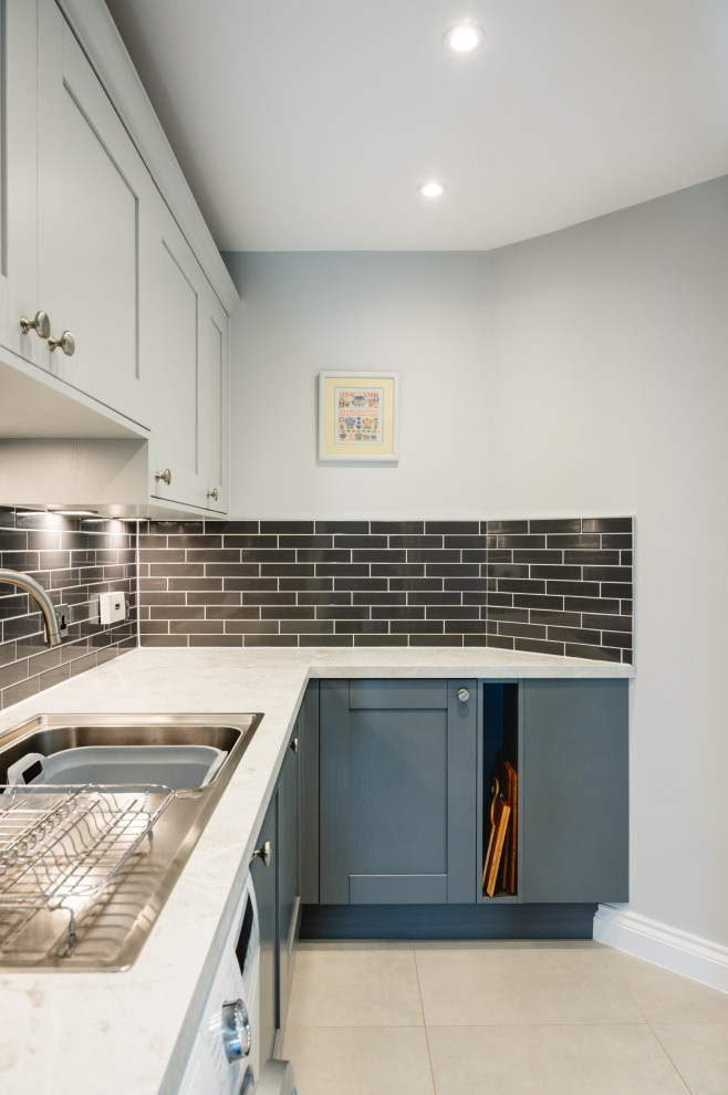 Design ideas for a mid-sized traditional l-shaped utility room in Surrey with a single-bowl sink, shaker cabinets, grey cabinets, laminate benchtops, grey splashback, ceramic splashback, grey walls, porcelain floors, grey floor and white benchtop.