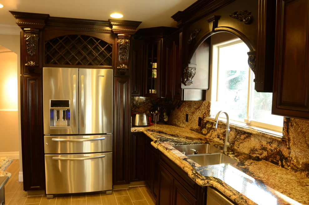 Photo of a mediterranean l-shaped kitchen in Other with an undermount sink, beaded inset cabinets, dark wood cabinets, granite benchtops, stone slab splashback, stainless steel appliances and ceramic floors.