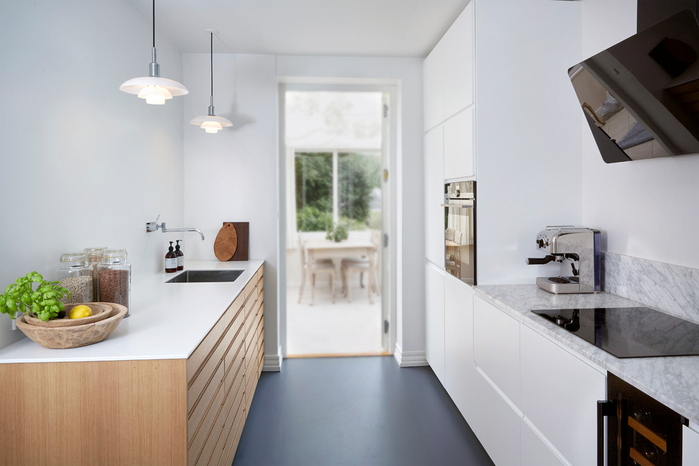 Photo of a mid-sized traditional galley separate kitchen in Aarhus with an undermount sink, flat-panel cabinets, light wood cabinets, marble benchtops, grey splashback, marble splashback, black appliances, linoleum floors, a peninsula, blue floor and multi-coloured benchtop.