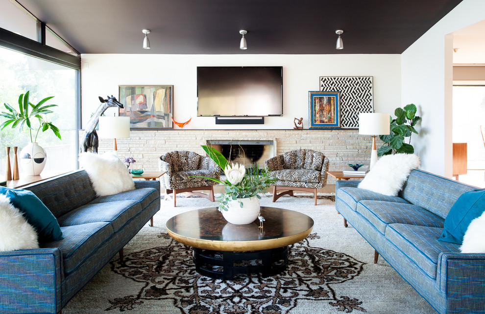 Eclectic living room in Austin with white walls, a standard fireplace, a stone fireplace surround and a wall-mounted tv.