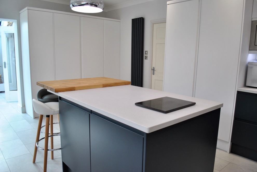 This is an example of a mid-sized scandinavian u-shaped separate kitchen in Hertfordshire with a drop-in sink, flat-panel cabinets, stainless steel appliances, with island, grey floor and white benchtop.