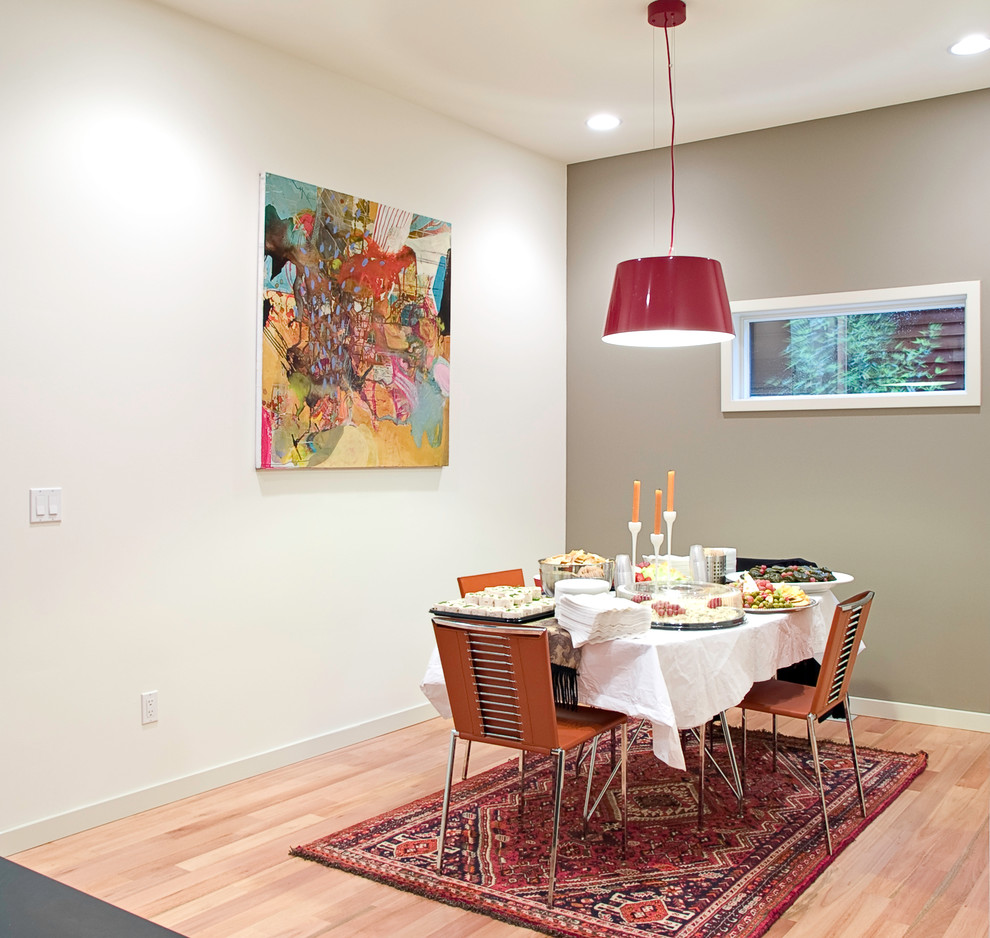 Photo of a modern dining room in Seattle with grey walls and medium hardwood floors.