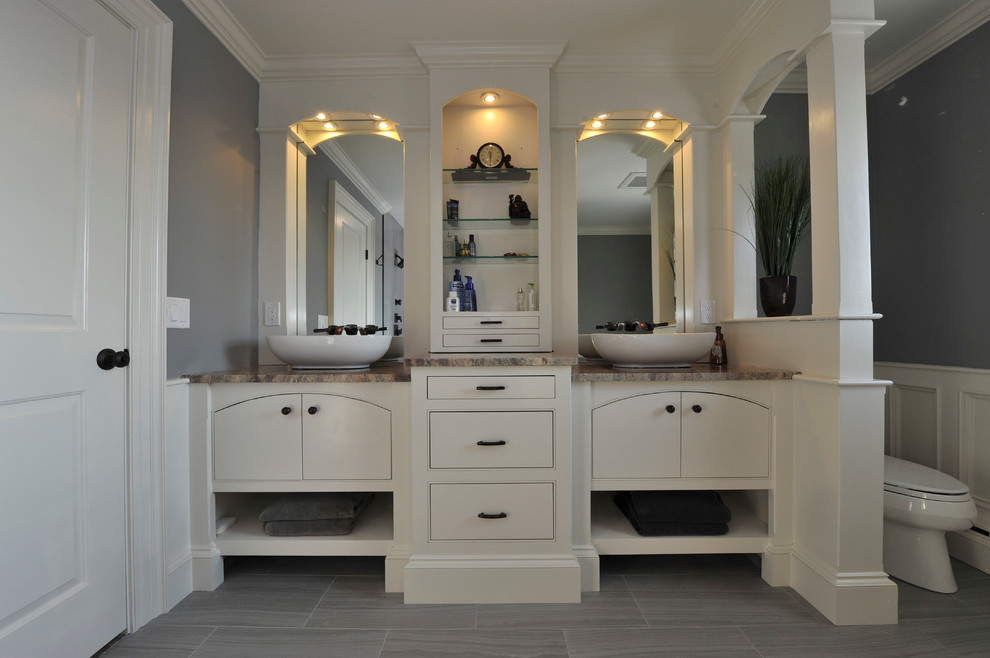 Photo of a transitional bathroom in New York with a vessel sink, beaded inset cabinets, white cabinets, granite benchtops, a drop-in tub, a double shower, a two-piece toilet, gray tile, porcelain tile, grey walls and porcelain floors.