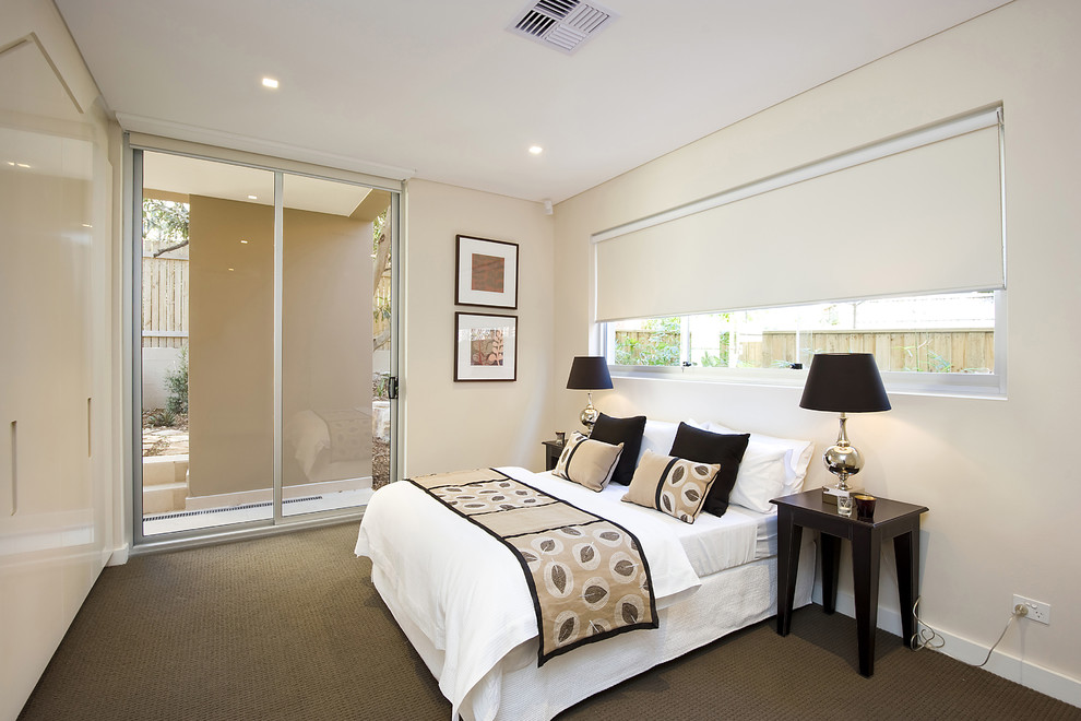 This is an example of a mid-sized contemporary guest bedroom in Other with white walls, carpet and brown floor.