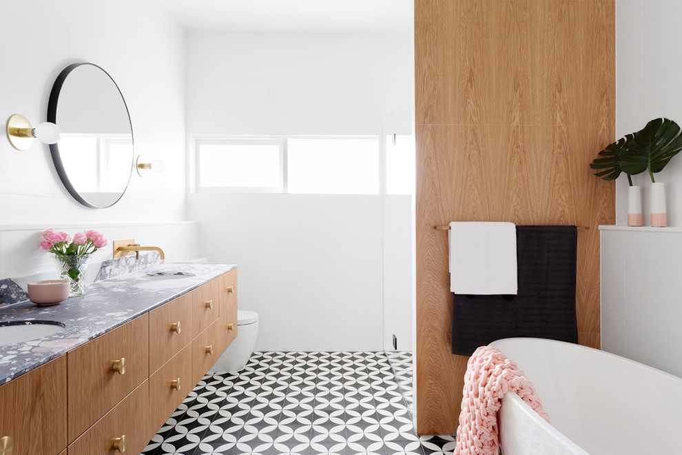 Inspiration for a large contemporary master bathroom in Melbourne with flat-panel cabinets, a freestanding tub, black floor, light wood cabinets, an alcove shower, a one-piece toilet, cement tile, cement tiles, an integrated sink and marble benchtops.