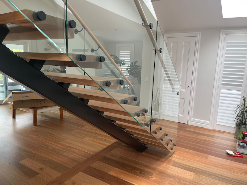 This is an example of a mid-sized modern wood floating staircase in Auckland with open risers and wood railing.