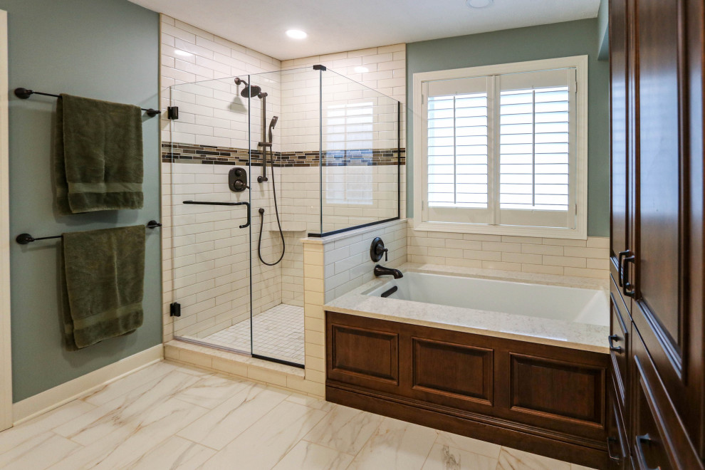 This is an example of a mid-sized traditional master bathroom in Cleveland with raised-panel cabinets, brown cabinets, a drop-in tub, a corner shower, a two-piece toilet, white tile, porcelain tile, green walls, cement tiles, an undermount sink, engineered quartz benchtops, beige floor, a hinged shower door, beige benchtops, a double vanity and a freestanding vanity.