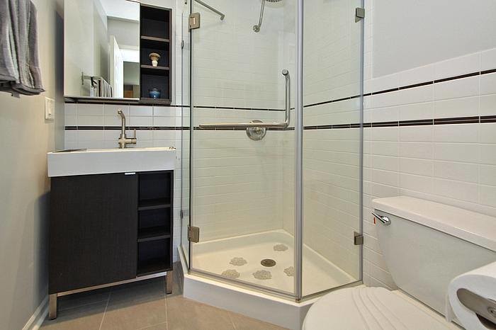 Inspiration for a small contemporary 3/4 bathroom in Chicago with furniture-like cabinets, dark wood cabinets, solid surface benchtops, a corner shower, a one-piece toilet, white tile, porcelain tile, grey walls and porcelain floors.