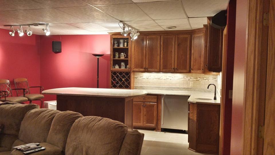 Photo of a mid-sized traditional l-shaped seated home bar in Minneapolis with an undermount sink, recessed-panel cabinets, dark wood cabinets, quartz benchtops, white splashback, ceramic splashback, grey floor and white benchtop.