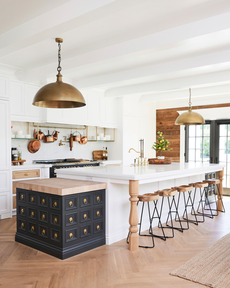 This is an example of a large transitional single-wall eat-in kitchen in Salt Lake City with a farmhouse sink, recessed-panel cabinets, quartz benchtops, white splashback, engineered quartz splashback, panelled appliances, light hardwood floors, with island, white benchtop and exposed beam.