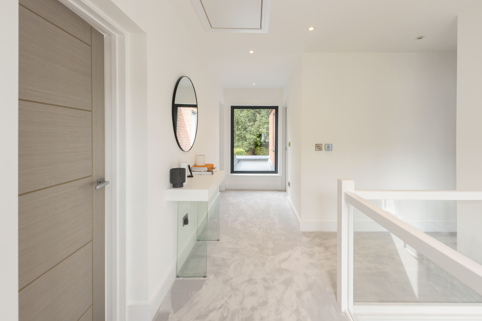 Cette image montre un grand couloir design avec un mur blanc, un sol en carrelage de porcelaine et un sol beige.