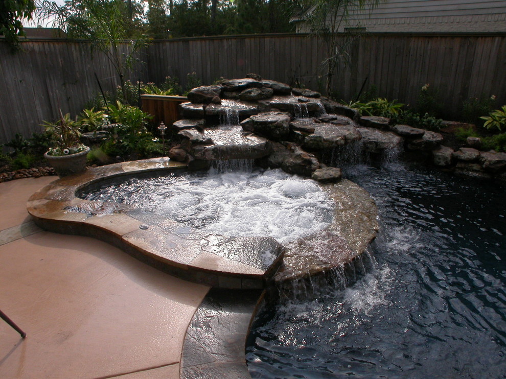 Inspiration for a large contemporary backyard custom-shaped natural pool in Houston with a hot tub and natural stone pavers.
