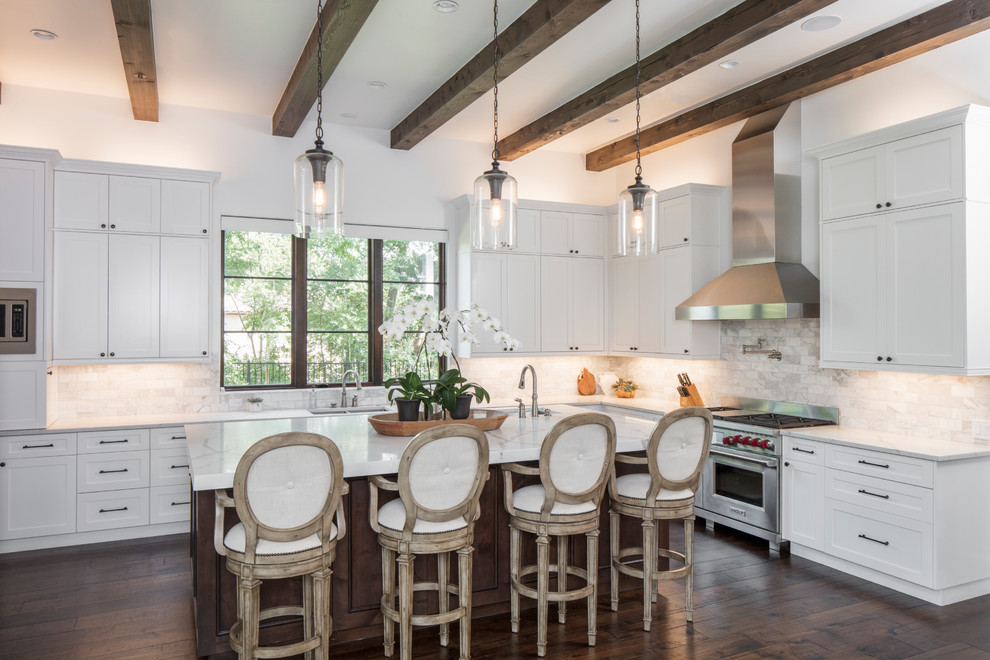 Inspiration for a large mediterranean l-shaped open plan kitchen in Austin with a double-bowl sink, shaker cabinets, white cabinets, white splashback, stainless steel appliances, dark hardwood floors, with island, brown floor, marble benchtops and marble splashback.