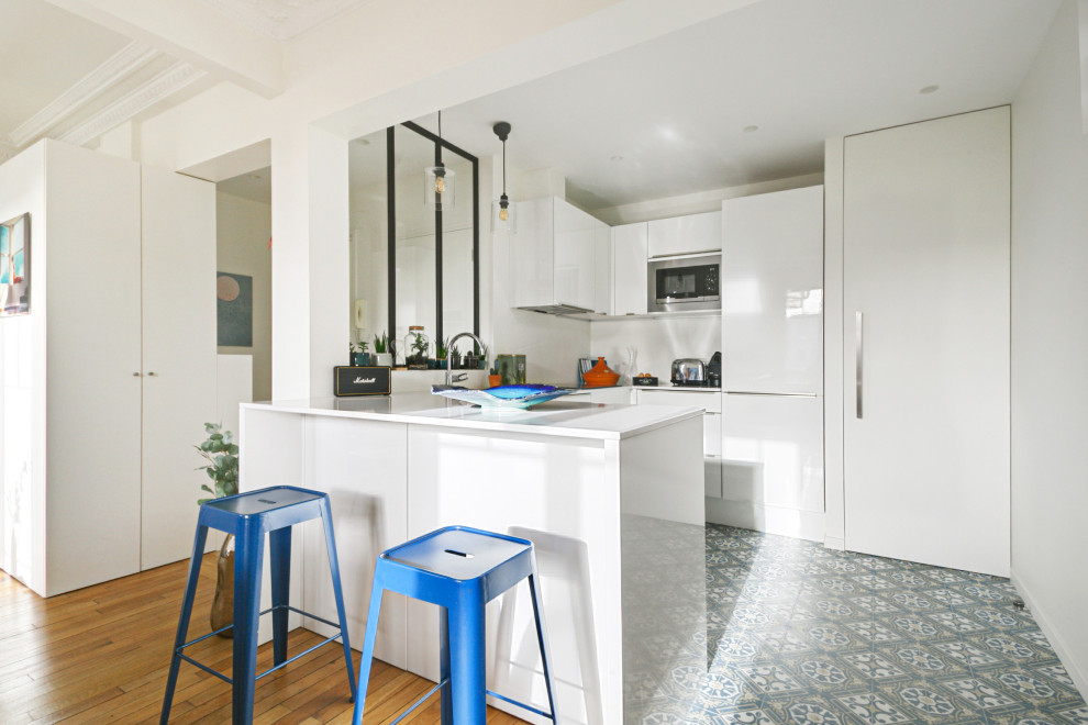 Inspiration for a mid-sized contemporary u-shaped open plan kitchen in Paris with an undermount sink, beaded inset cabinets, white cabinets, quartz benchtops, white splashback, panelled appliances, cement tiles, with island, blue floor and white benchtop.