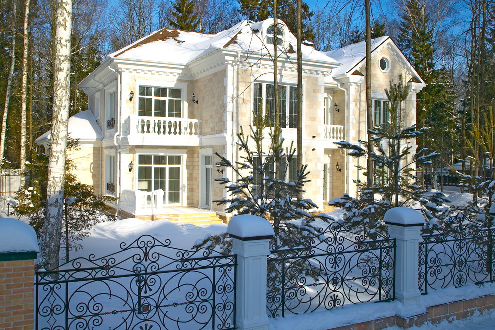 This is an example of a mid-sized traditional two-storey beige house exterior in Moscow with stone veneer, a gambrel roof and a green roof.