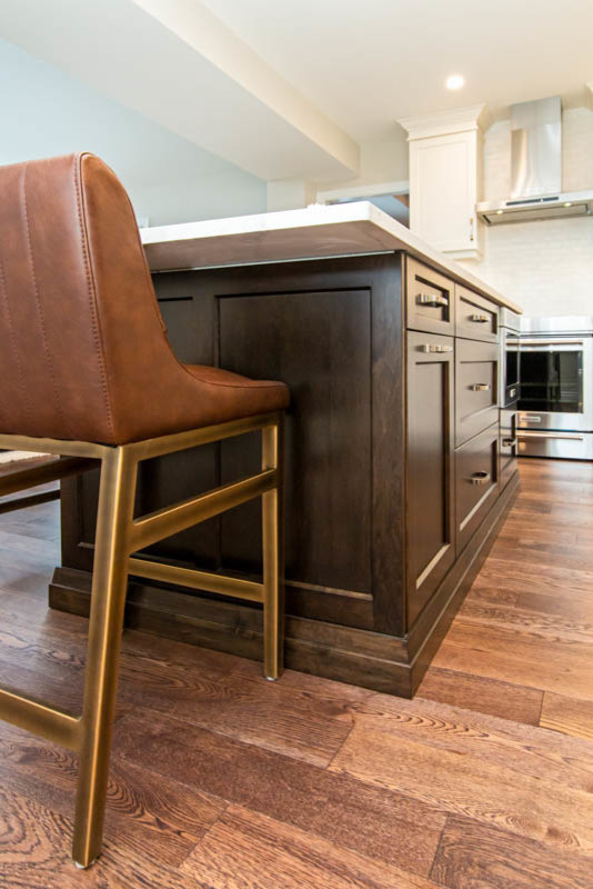 Inspiration for a mid-sized transitional l-shaped medium tone wood floor and brown floor open concept kitchen remodel with an undermount sink, shaker cabinets, white cabinets, quartzite countertops, white backsplash, stone tile backsplash, stainless steel appliances, an island and white countertops