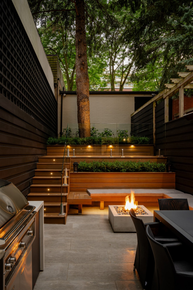 This is an example of a small contemporary backyard patio in Toronto with an outdoor kitchen, concrete pavers and no cover.