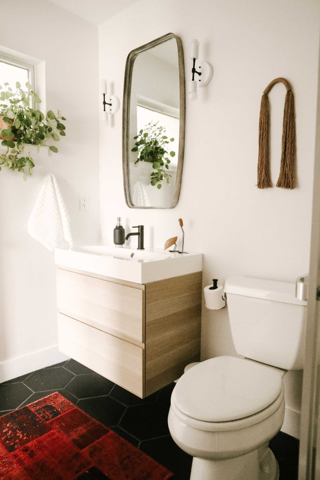 Small midcentury kids bathroom in Other with flat-panel cabinets, light wood cabinets, a one-piece toilet, white walls, porcelain floors, an integrated sink, black floor, a sliding shower screen, white benchtops, a single vanity and a floating vanity.
