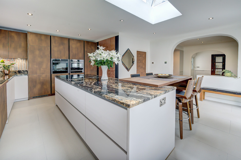 This is an example of a large contemporary eat-in kitchen in London with white cabinets, granite benchtops, metallic splashback, glass tile splashback, black appliances, with island, grey floor and orange benchtop.